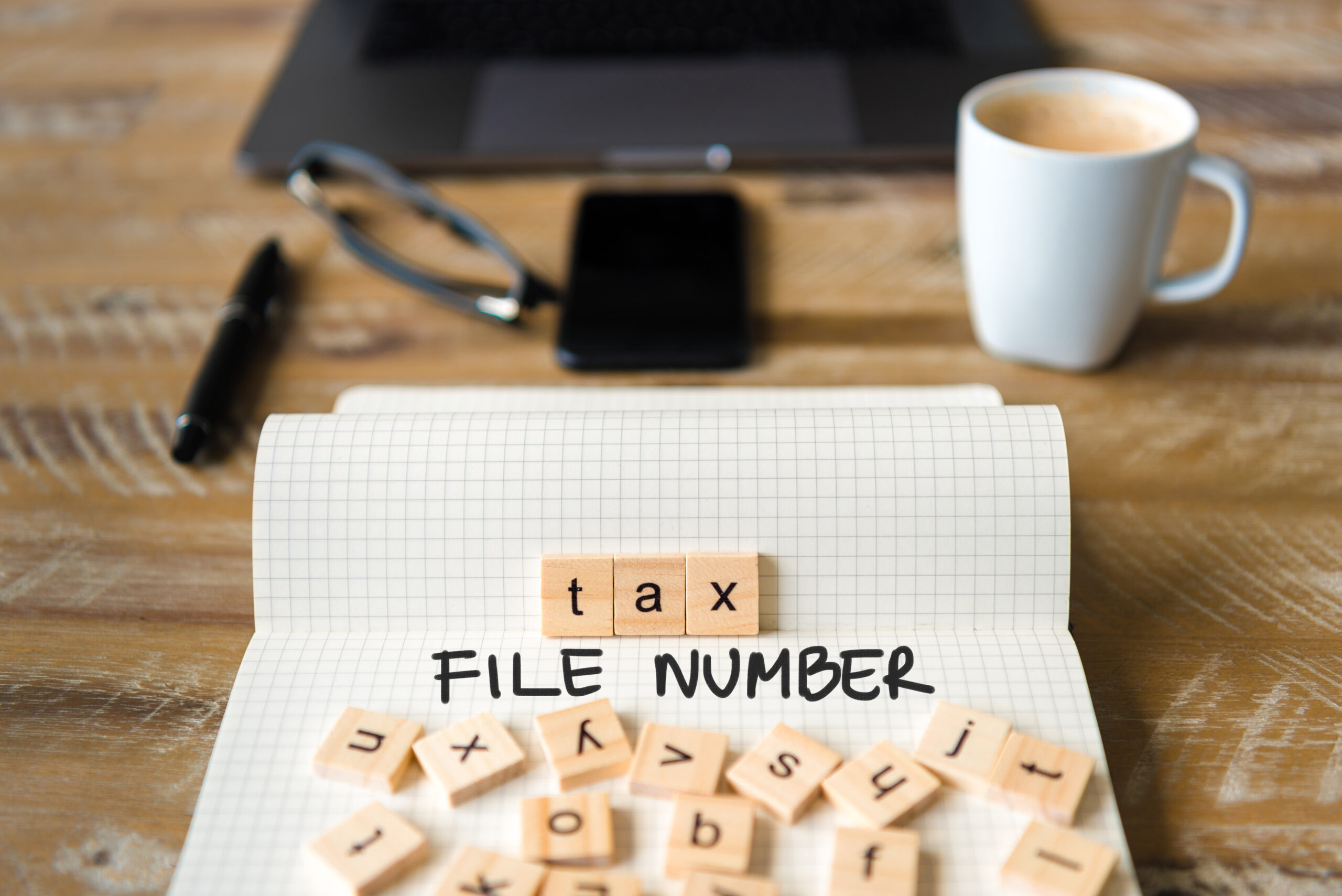 Closeup on notebook over vintage desk background, front focus on wooden blocks with letters making Tax File Number TFN text